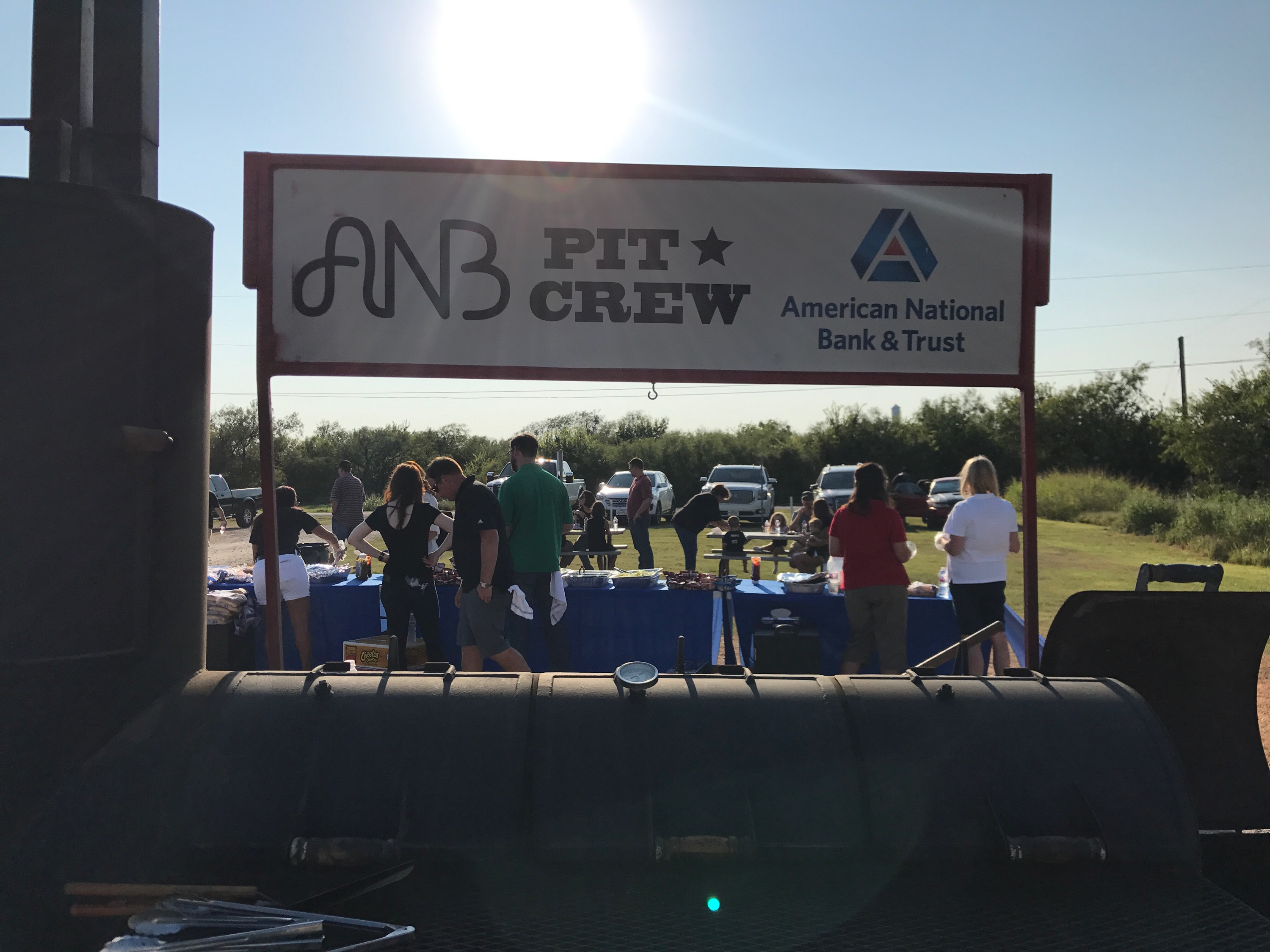 Employees serving food at a cookout in front of a cooker