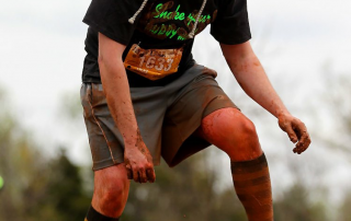 Bryan Hines climbing on top of a muddy hill.